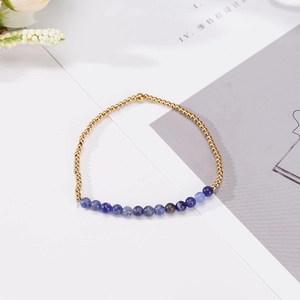 Pulsera minimalista de cuentas doradas y piedra natural azul para parejas sobre fondo blanco