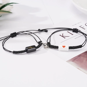 Pair of adjustable black woven magnetic couple bracelets with heartbeat and heart charms