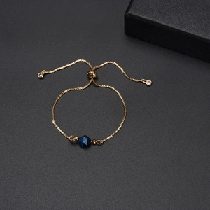 Elegant gold bracelet with faceted blue gemstone and adjustable slider chain in a gift box