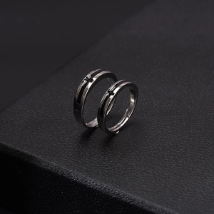 Minimalist silver cross couple rings on black leather texture with elegant lighting