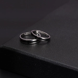 Minimalist stainless steel cross couple rings with black inlay on dark leather base
