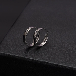 Anelli di coppia minimalisti in argento con finitura lucida su sfondo in pelle nera testurizzata