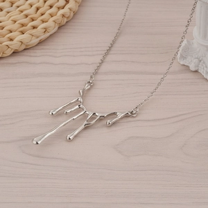 Collier goutte de lave liquide en métal argenté sur fond en bois minimaliste élégant