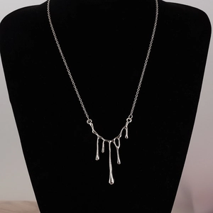 Collier avec pendentif goutte d'eau en métal argenté poli sur un présentoir à bijoux