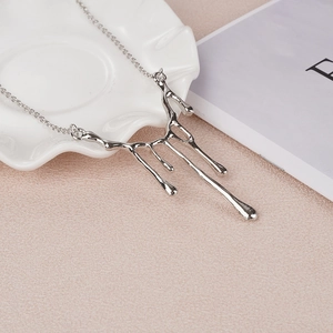 Collier à pendentif goutte de lave argentée polie pour femme sur fond minimaliste chic