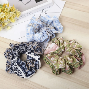 Three-pack of floral fabric scrunchies with bohemian patterns on a light wooden background