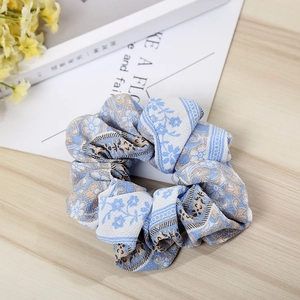 Detailed close-up of light blue bohemian floral scrunchie with soft fabric texture