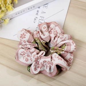 Detail of floral scrunchie with pink blossoms on light chiffon fabric and wood background