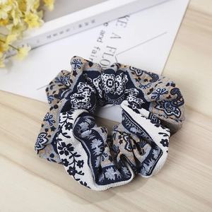 Detailed view of bohemian floral print scrunchie on a soft wood texture background