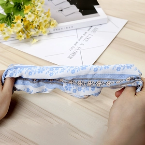 Macro shot of blue floral fabric scrunchie being stretched to show its high elasticity