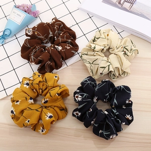 Detail view of four floral daisy fabric scrunchies in assorted retro earth tone colors