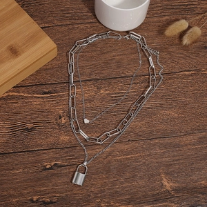 Detail of silver layered necklace with heart and padlock pendants on a wooden surface