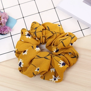 Close-up of yellow floral scrunchie with white daisy print on soft chiffon fabric