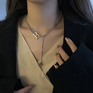 Close-up of silver Cuban chain necklace featuring a bold letter B pendant and tassel