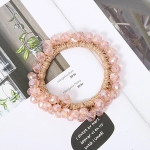 Detailansicht der rosa Kristallperlen und des goldenen elastischen Zopfgummis