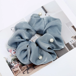 Close-up of a blue satin scrunchie with elegant faux pearl details on a magazine