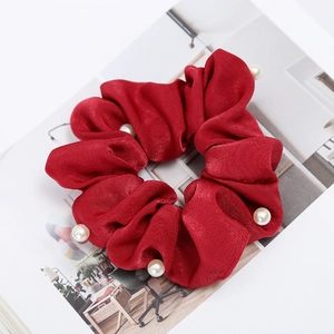 Detailed close-up of a burgundy satin scrunchie featuring elegant inlaid white pearls