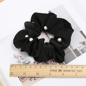 Close-up of black satin hair scrunchie with white pearls and measuring ruler