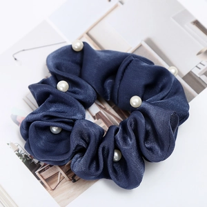Detailed view of dark blue satin scrunchie with elegant faux pearl embellishments