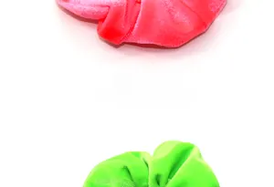 Vista dettagliata di scrunchies in velluto rosa e verde fluo con fasce elastiche