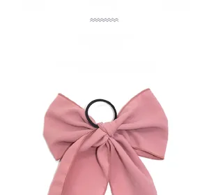 Close-up of pink bow hair scrunchie made of soft fabric with elastic band detail
