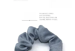 Dettaglio ravvicinato dell'elastico per capelli grigio-blu plissettato in velluto