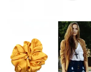 Detail of a large yellow satin hair scrunchie with shiny silk texture and pleated design