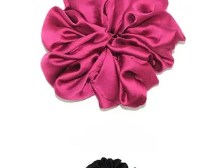 Macro detail of large rose red satin silk scrunchie with smooth pleated texture