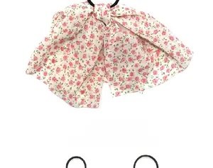Close-up of white chiffon bow hair tie with pink floral pattern and black elastic band