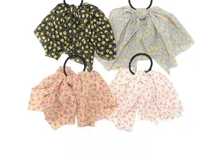 Detailed view of four chiffon floral bow hair ties in black, blue, beige, and white colors