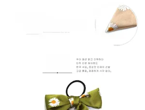 Detail of green daisy print bow hair tie with smooth fabric texture and elastic band