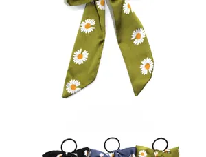 Detail view of satin daisy print hair scrunchies with long ribbons in multiple colors