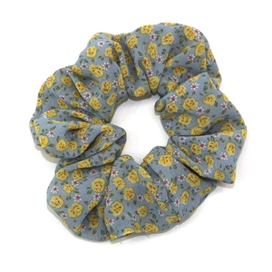 Chouchou en mousseline bleu clair avec motif floral jaune sur fond blanc