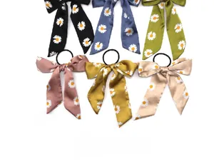 Flat lay detail of six colorful daisy print bow hair ties with long satin ribbons