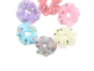 Détail de chouchous en organza coloré remplis de mini boules de peluche sur fond blanc