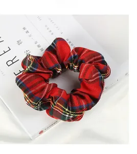 Détail d'un chouchou à carreaux rouges posé sur un magazine blanc au style minimaliste