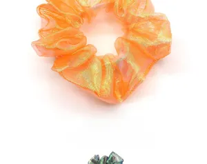 Detail view of shimmering orange organza scrunchie with metallic reflective fabric texture