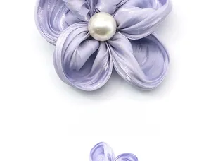 Détail d'une barrette fleur en soie violette avec perle centrale et texture douce