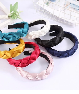 Detail showing various colors of braided silk satin headbands in a lifestyle setting