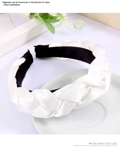 Detail of a white braided silk satin headband featuring a black non-slip inner lining