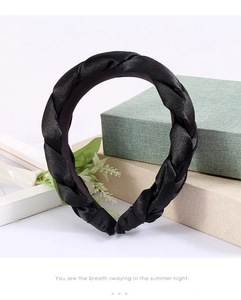 Detailed close-up of a black braided satin headband with an elegant glossy finish