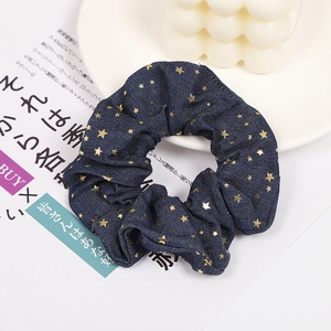 Detail of navy blue denim scrunchie with gold star patterns on a white decorative setting