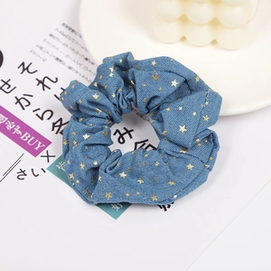 Detailed shot of blue denim hair scrunchie with golden star patterns and lace accents