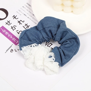 Detail of blue denim hair scrunchie with delicate white lace trim and ruffled texture