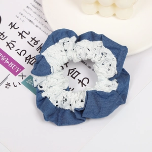 Detailed shot of dark blue denim hair scrunchie with white floral lace trim and texture