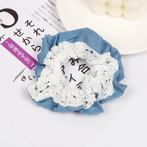 Detailed view of denim fabric hair scrunchie with white lace trim and ruffled edges