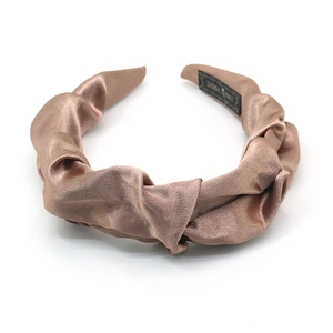 Fashionable champagne satin pleated headband with a handmade label on a white background