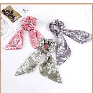 Detail of three silk bow scrunchies with vintage floral patterns in pink, purple, and green