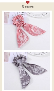 Detail of silk-like paisley bow scrunchies with long ribbons in pink and gray colors