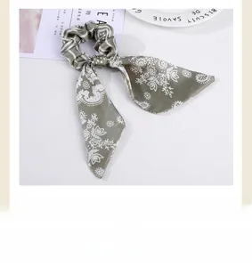 Detail of grey-green satin hair scrunchie with long ribbon and white floral patterns